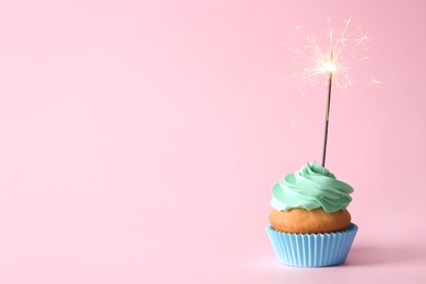 Photo of Delicious birthday cupcake with burning sparkler and space for text on color background