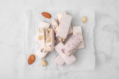 Photo of Pieces of delicious nutty nougat on white table, top view