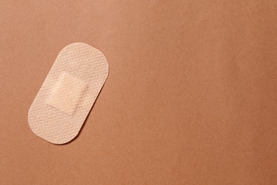 Photo of Contraceptive patch on light brown background, top view. Space for text