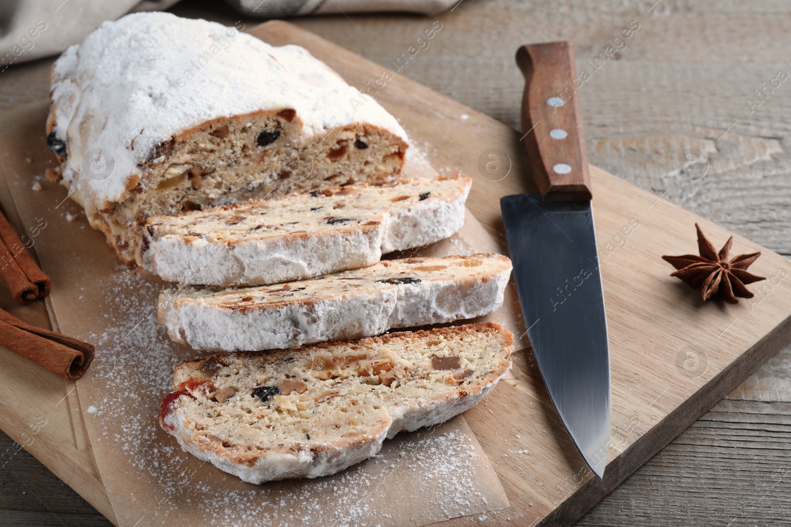 Photo of Traditional Christmas Stollen with icing sugar on wooden table