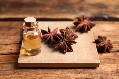 Bottle of essential oil and anise on wooden table