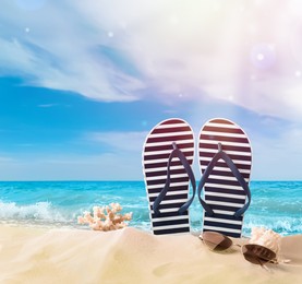 Image of Striped flip flops, coral, sea shell and sunglasses on sandy beach 