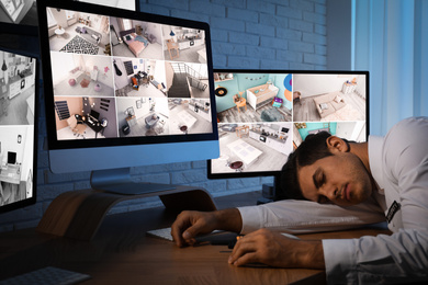 Male security guard sleeping near monitors at workplace