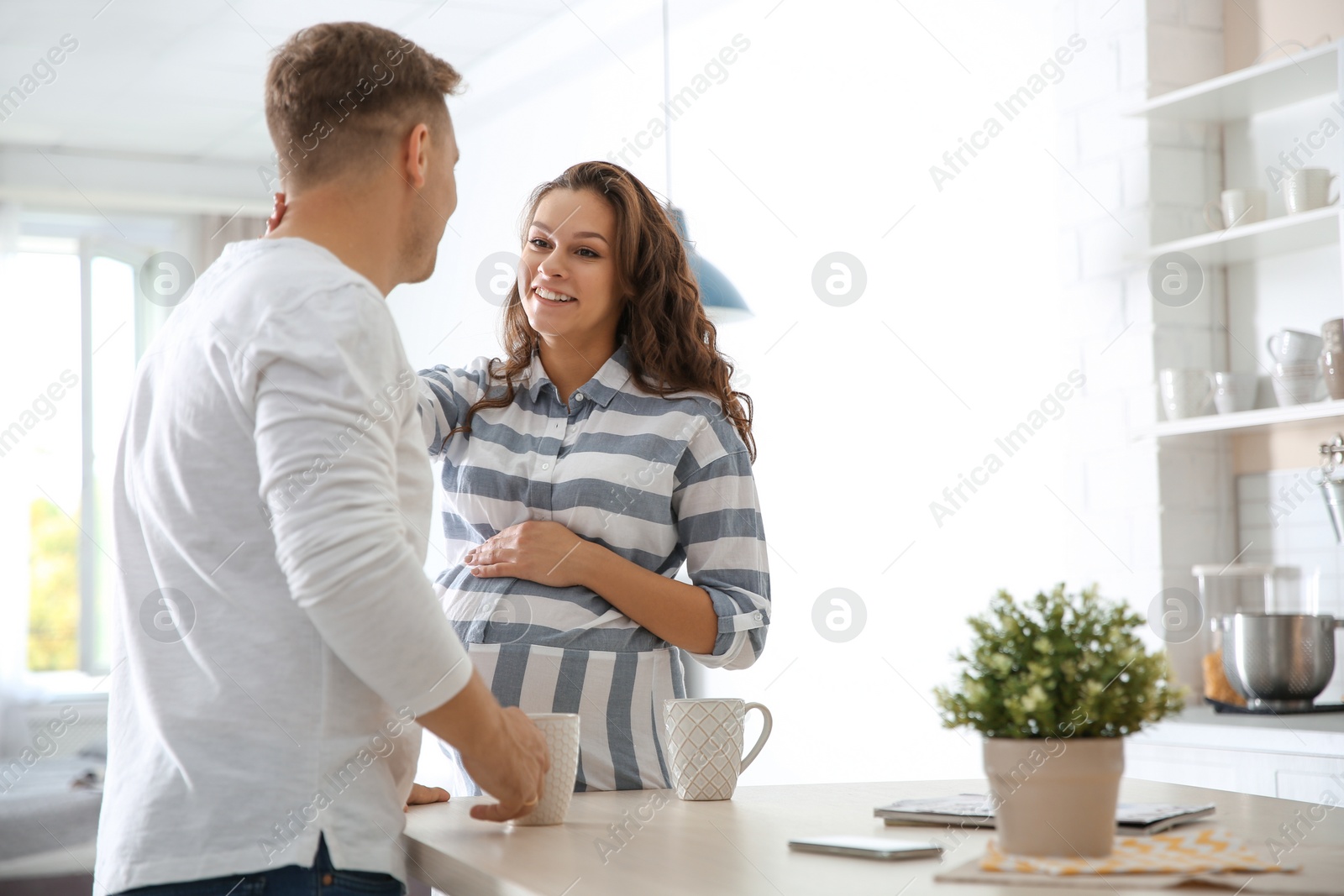 Photo of Pregnant woman with her husband in kitchen. Space for text