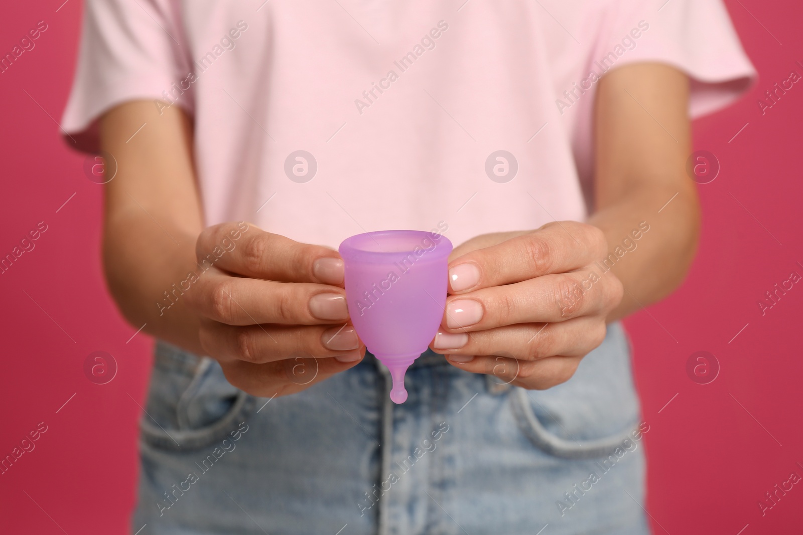 Photo of Young woman with menstrual cup on bright pink background, closeup