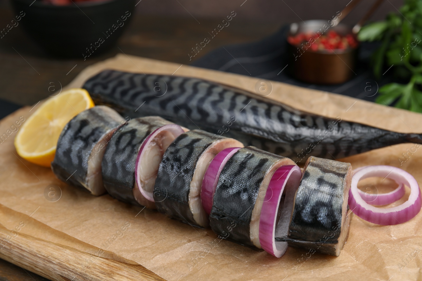 Photo of Tasty salted mackerel, onion and lemon on parchment, closeup