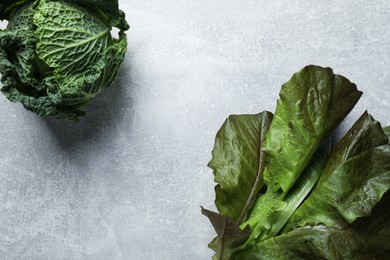 Photo of Fresh ripe savoy cabbage and cos lettuce on grey table, flat lay. Space for text