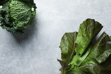 Fresh ripe savoy cabbage and cos lettuce on grey table, flat lay. Space for text