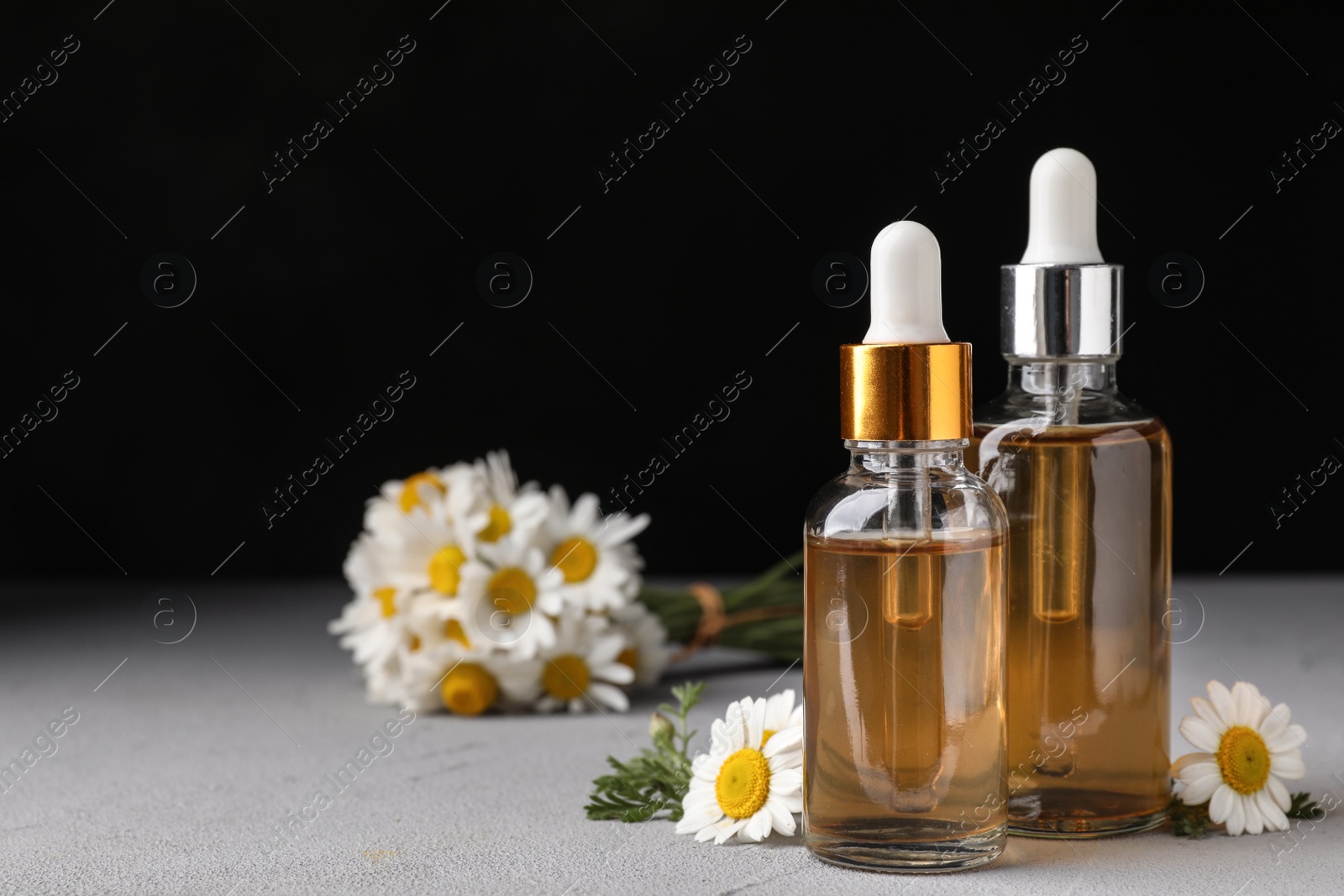 Photo of Composition with bottles of chamomile essential oil on table. Space for text