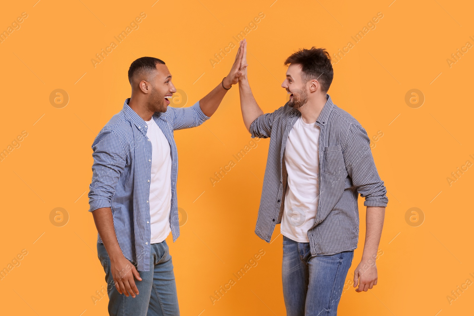 Photo of Men giving high five on yellow background
