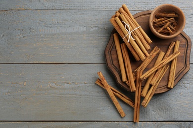 Photo of Aromatic cinnamon sticks on grey wooden table, flat lay. Space for text