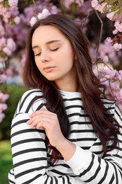 Beautiful woman near blossoming tree on spring day