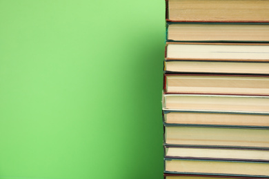 Photo of Stack of hardcover books on green background. Space for text