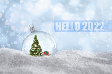 Image of Hello 2022. Beautiful glass ball with Christmas tree and gift on snow against light blue background