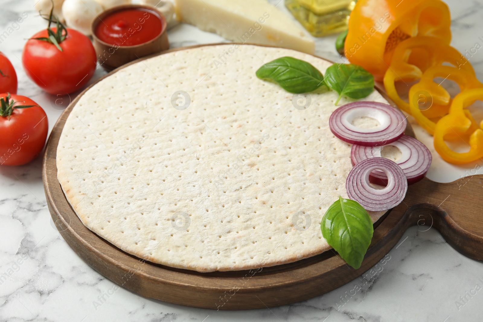 Photo of Base and ingredients for pizza on marble table