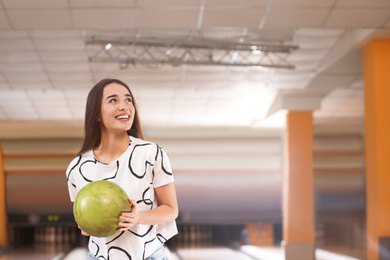 Photo of Young woman with ball in bowling club. Space for text