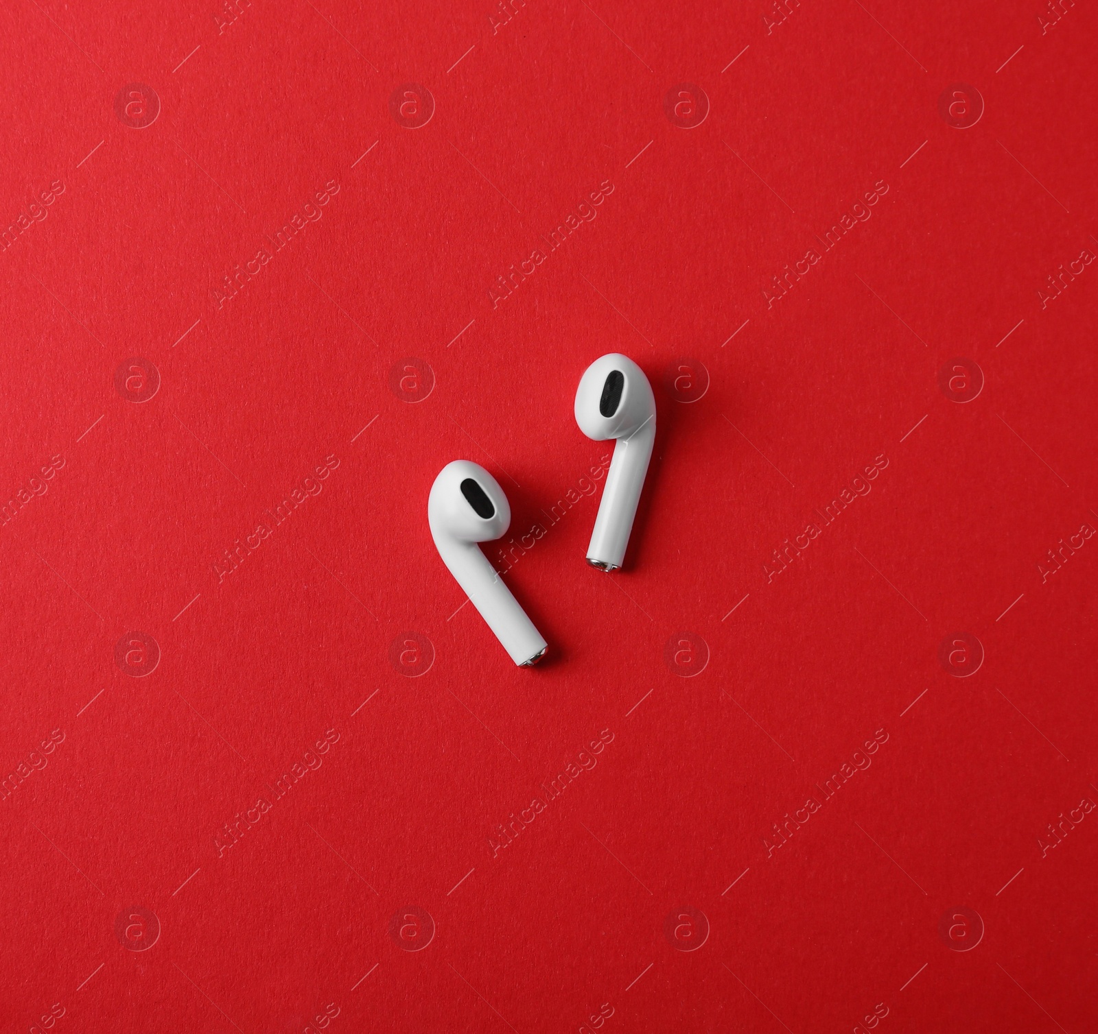 Photo of Modern wireless earphones on red background, flat lay. Space for text