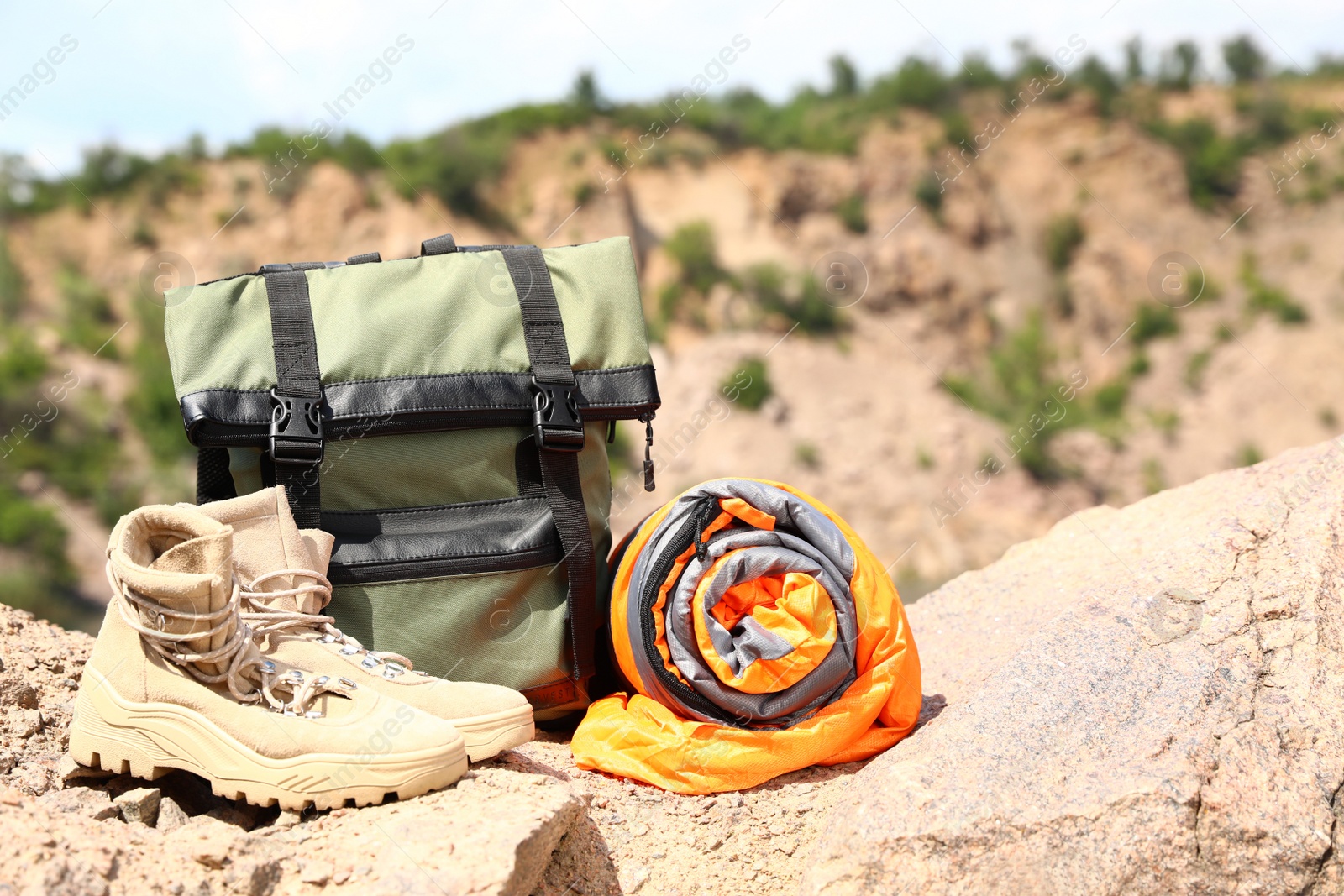 Photo of Backpack with sleeping bag and boots outdoors on sunny day. Space for text