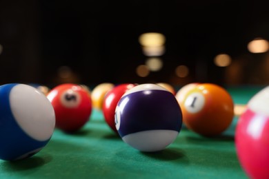 Photo of Many colorful billiard balls on green table, closeup