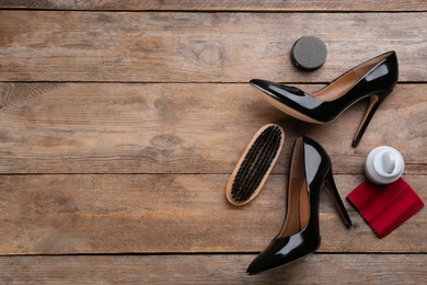 Flat lay composition with shoe care accessories and footwear on wooden background. Space for text