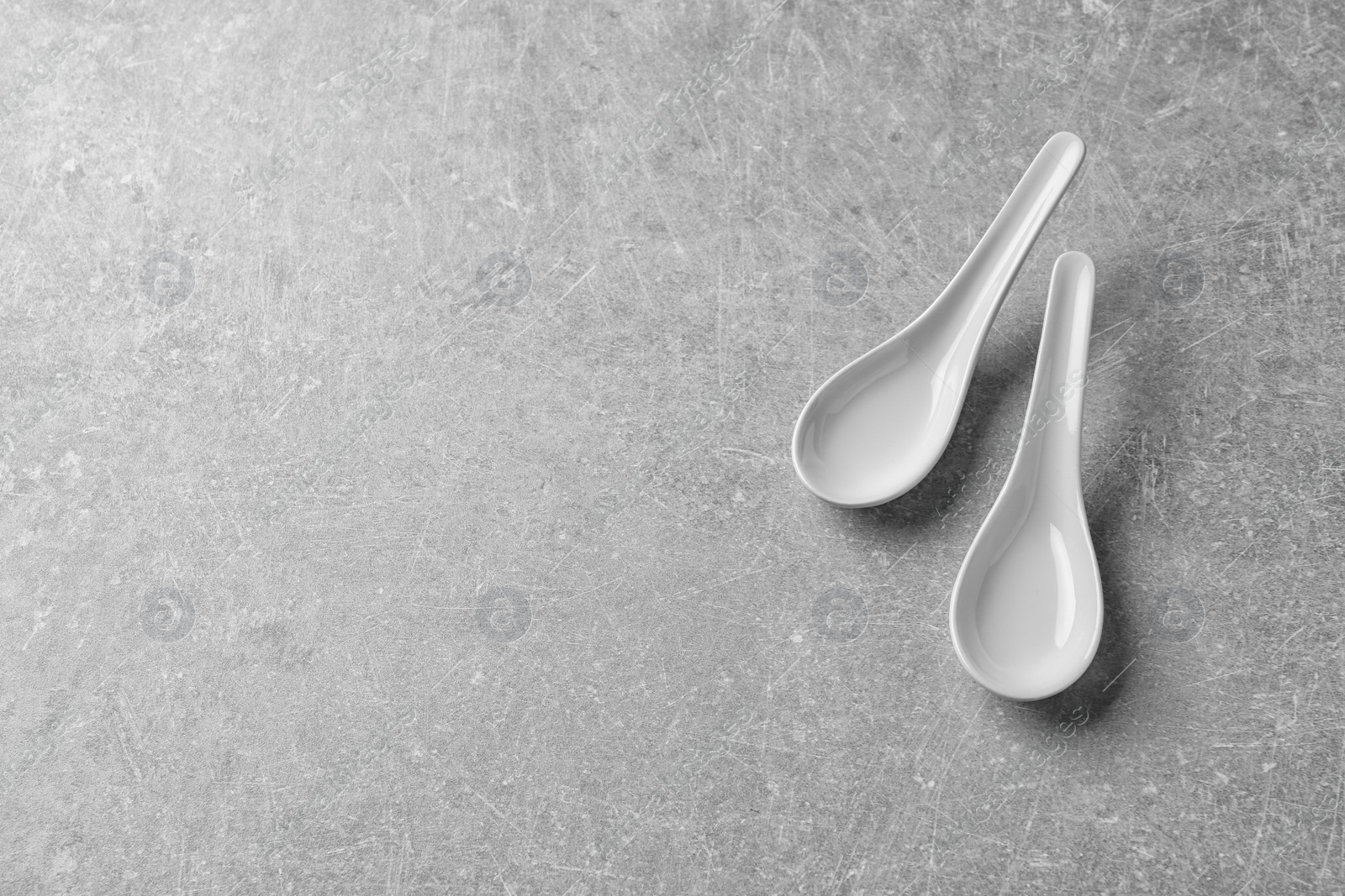 Photo of Miso soup spoons on grey background, above view. Space for text