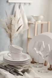 Photo of Set of clean dishware, cutlery and wineglasses on white table indoors