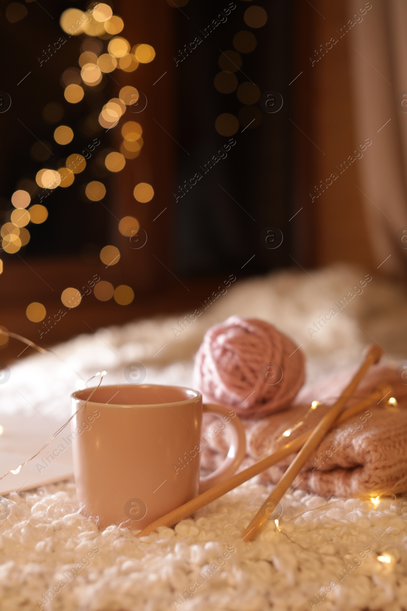 Photo of Composition with cup of hot beverage and knitting yarn on fuzzy rug. Winter evening