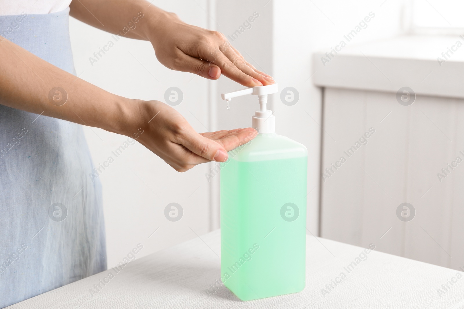 Photo of Woman applying antiseptic gel on hand indoors, closeup