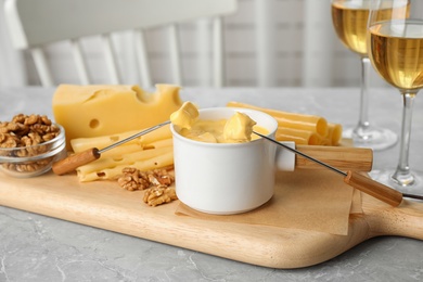 Pot of tasty cheese fondue served on grey table indoors