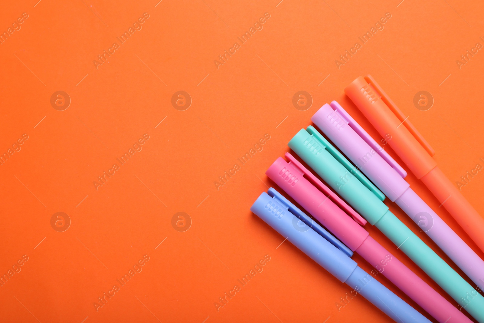 Photo of Many colorful markers on orange background, flat lay. Space for text