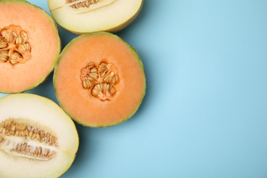 Photo of Tasty colorful ripe melons on light blue background, flat lay. Space for text