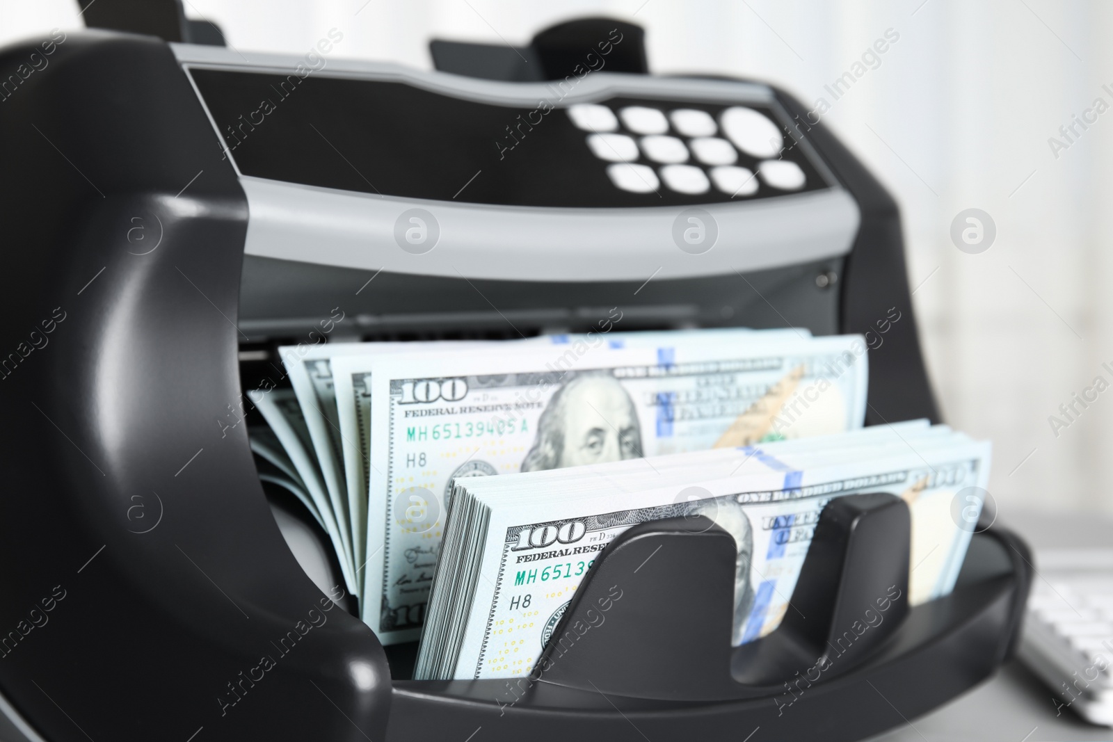 Photo of Modern electronic bill counter with money on table indoors, closeup