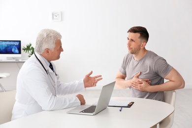 Photo of Male doctor working with patient in clinic. Cardiology consultation