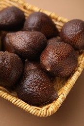 Delicious salak fruits in basket on pale brown background, closeup