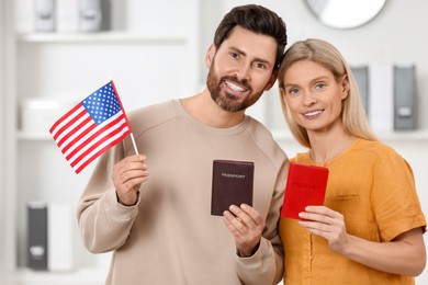 Photo of Immigration. Happy couple with passports and American flag indoors