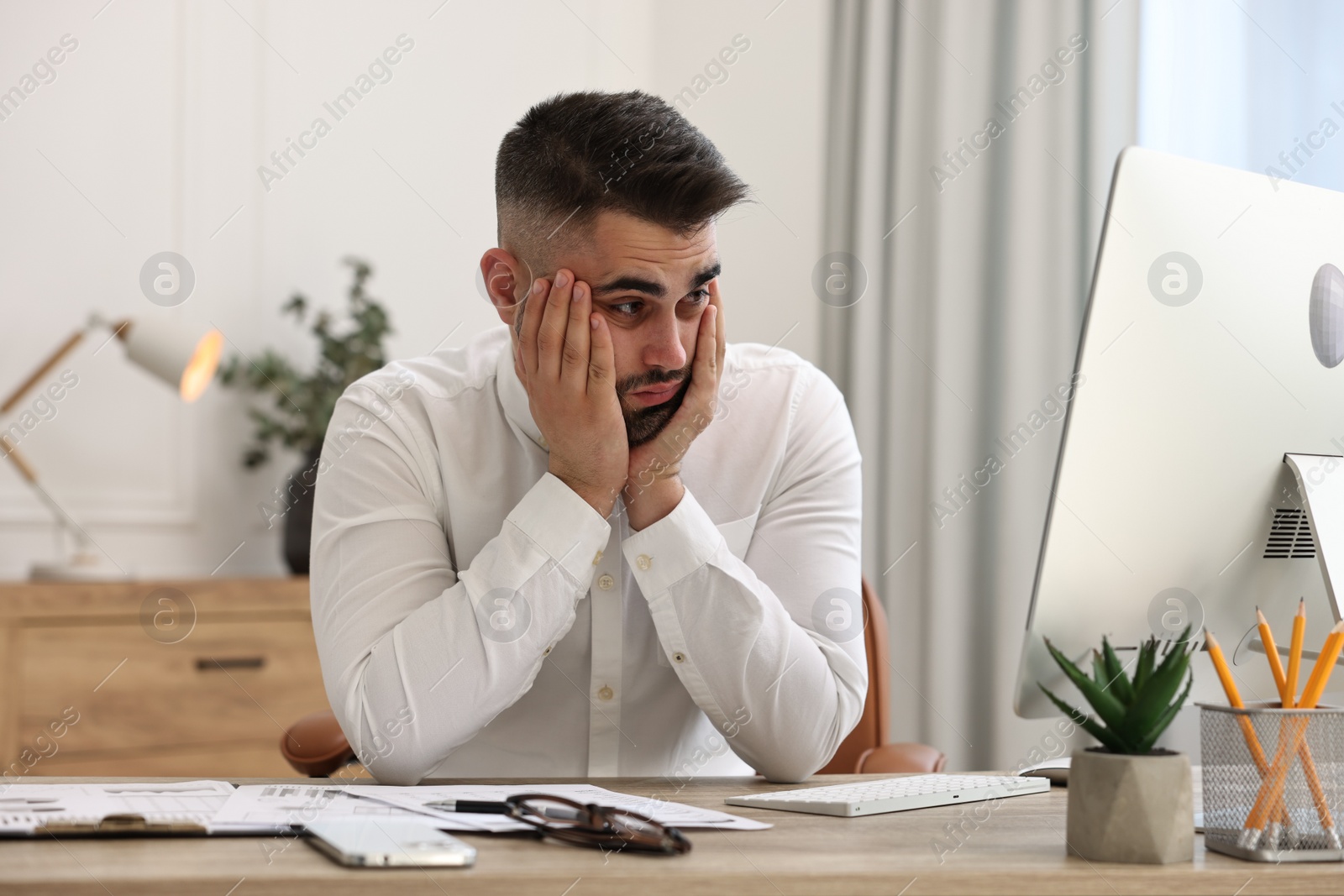 Photo of Overwhelmed man sitting at table in office