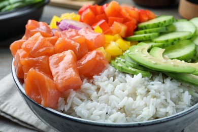 Delicious poke bowl with salmon and vegetables on table, closeup