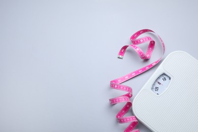 Photo of Scales and measuring tape on light grey background, flat lay. Space for text