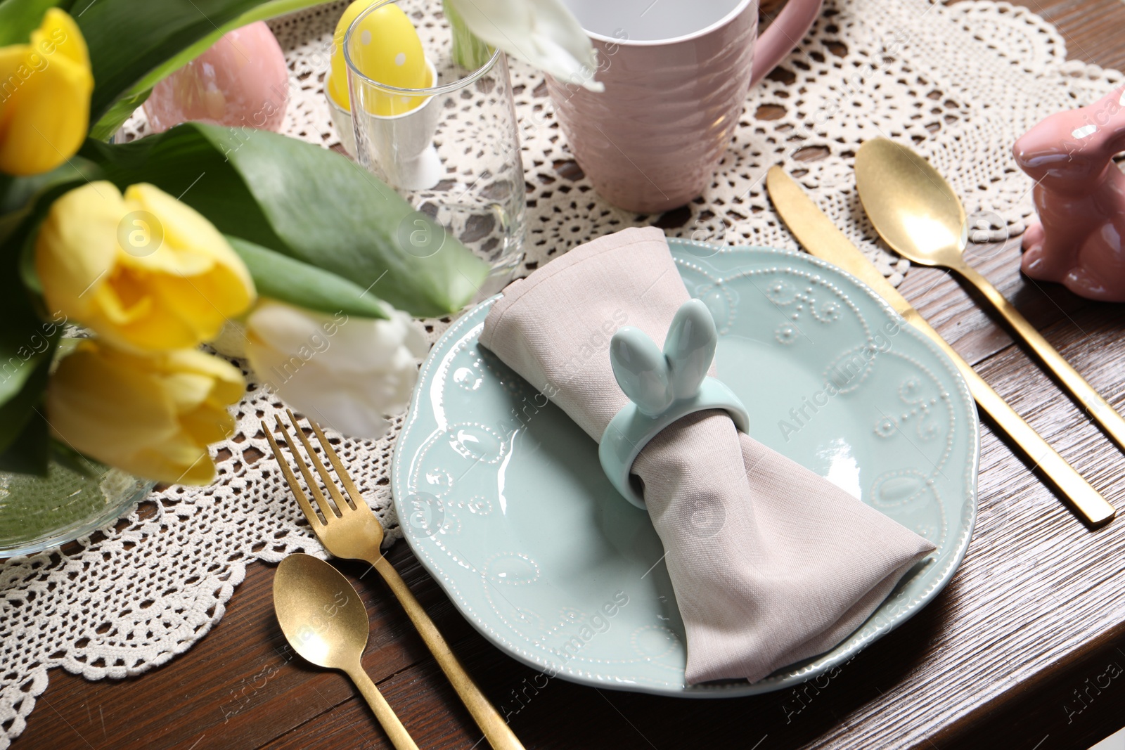 Photo of Festive table setting with napkin ring in shape of bunny ears, closeup. Easter celebration