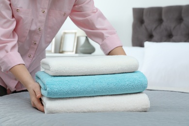 Woman putting stack of clean towels on bed