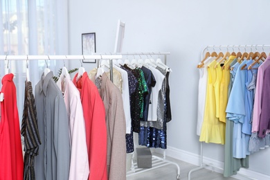 Wardrobe racks with different stylish clothes in light room