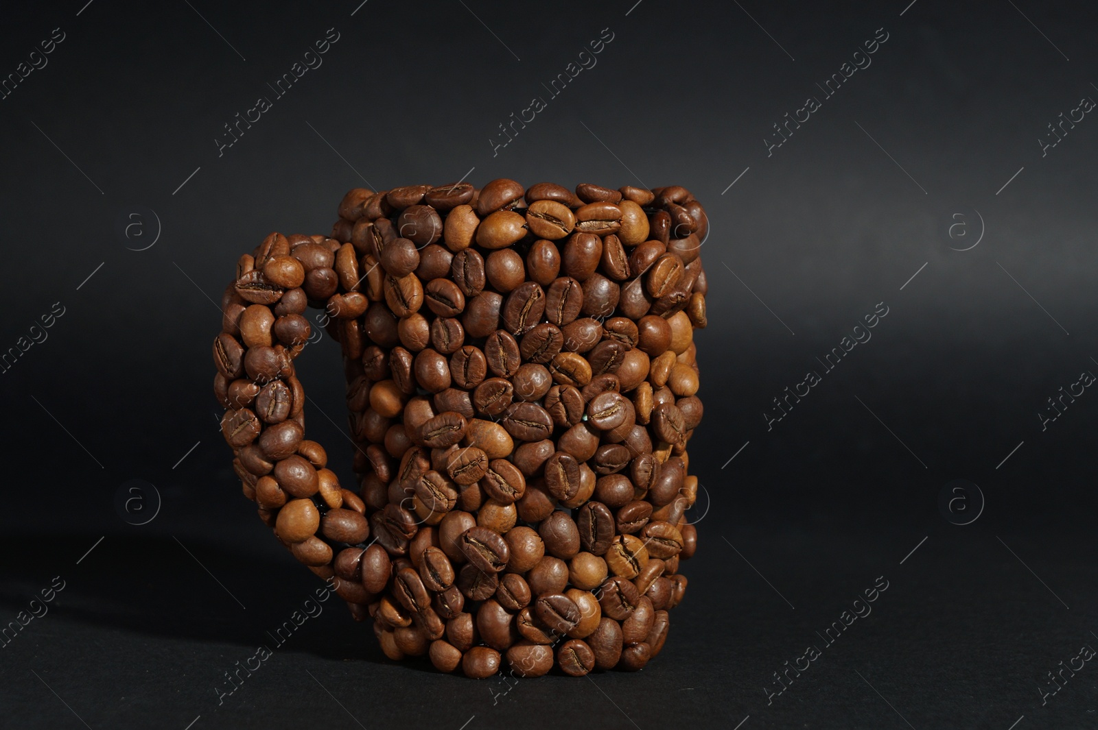 Photo of Cup made of coffee beans against black background