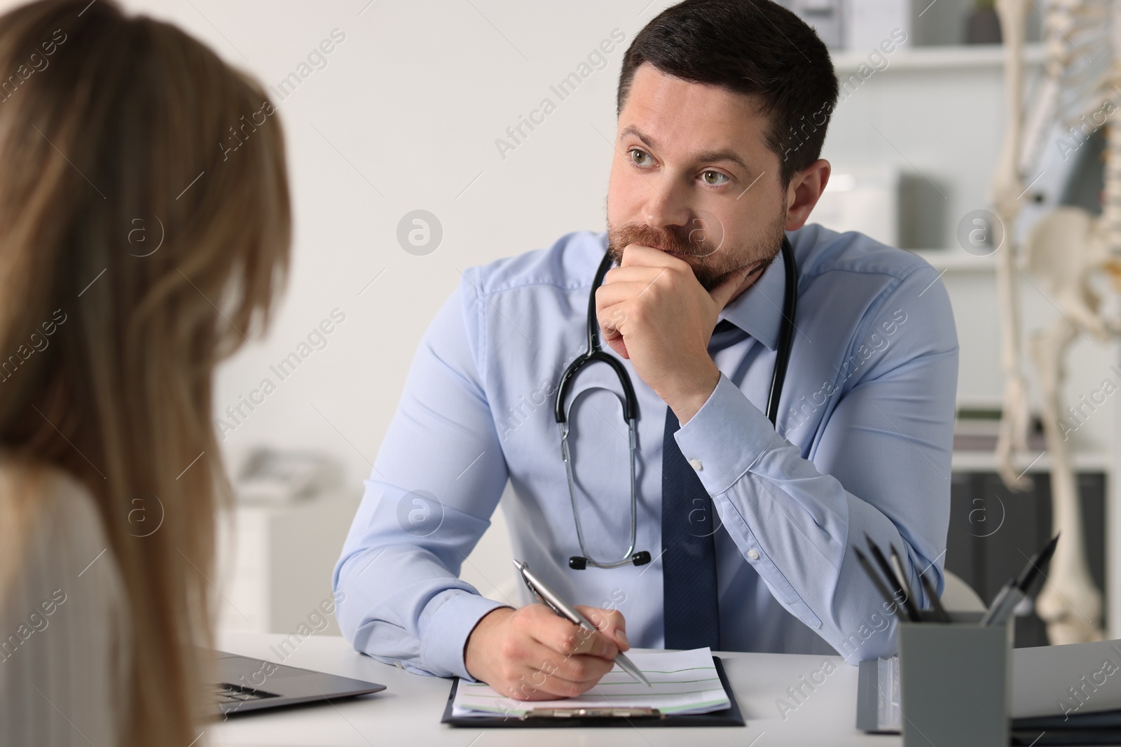 Photo of Professional doctor working with patient at white table in hospital