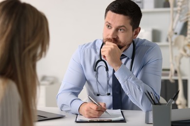 Professional doctor working with patient at white table in hospital