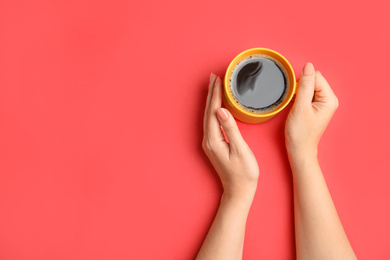 Woman with cup of coffee on red background, top view. Space for text