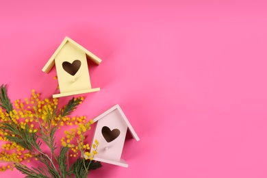 Photo of Beautiful bird houses and mimosa flowers on pink background, flat lay. Space for text