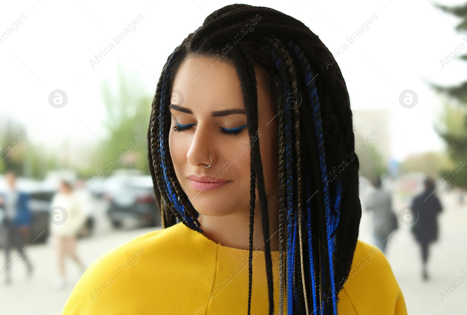 Photo of Beautiful young woman with nose piercing and dreadlocks outdoors