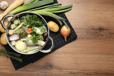 Pot and different ingredients for cooking tasty bouillon on wooden table, flat lay. Space for text