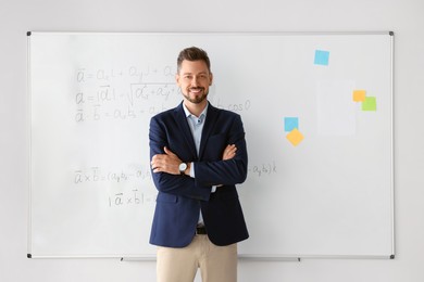Photo of Happy teacher at whiteboard in classroom during math lesson