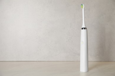 Photo of Electric toothbrush on light background, space for text